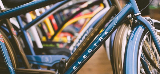 Electra electric bike in blue, side view, lined up with other bikes indoors
