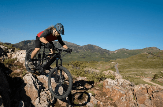 Black electric mountain bike side view ridden on rocky trail in outdoor landscape