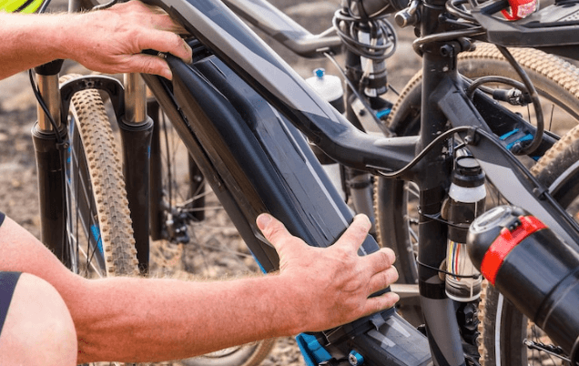 Close-up of electric bike battery being installed on black e-bike frame outdoors