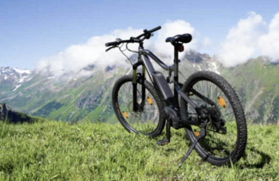 Electric mountain bike on grassy hill with scenic mountains, Pogo Cycles e bike store