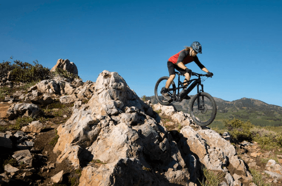Electric mountain bike with rider descending rocky trail in outdoor landscape