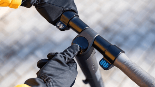 Close-up of a person pressing the power button on a black electric scooter handlebar