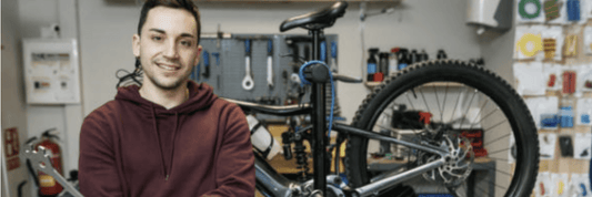 Electric mountain bike on repair stand with mechanic in workshop, side view