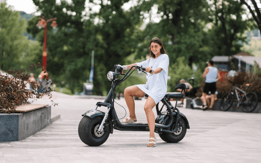 Woman riding a black electric scooter on a city street, side view