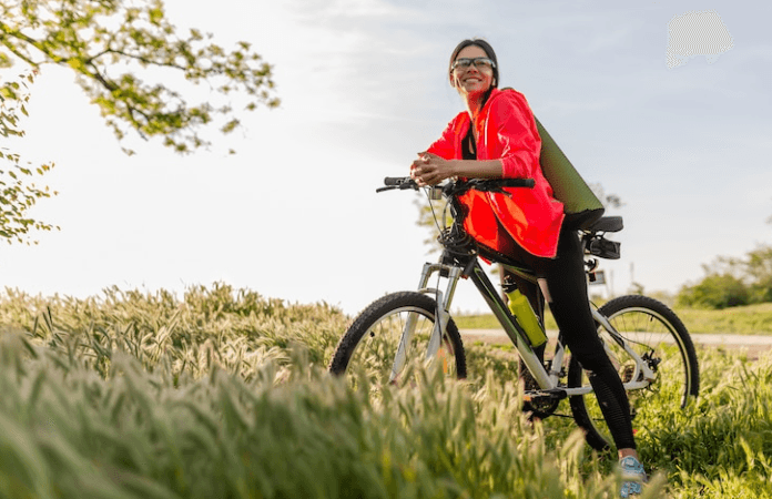 Electric bike with front suspension on grassy trail, side view with rider in outdoor setting